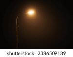Small photo of One night lamppost shines with faint mysterious yellow light through evening fog. Streetlight shine at quiet city night, magic atmospheric light in mystical darkness, copy space