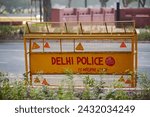 Small photo of Yellow Delhi police road barrier among road blocking way for people and cars, Malviya Nagar police road traffic barrier managing flow of people and vehicles