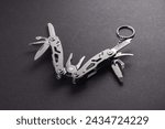 Small photo of multitool pliers on dark background. pocket knife multi-tool cut out