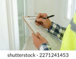 Small photo of inspector or engineer is inspecting construction and quality assurance new house using a checklist. Engineers or architects or contactor work to build the house before handing it over to the homeowner