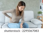 Small photo of Asia beautiful woman holding her lower back while and suffer from unbearable pain health and problems, chronic back pain, backache in office syndrome, scoliosis, herniated disc, muscle inflammation