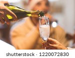 Christmas celebration with champagne - group of friends drinking and toasting together - a hand with bottle pouring sparkling wine in a glass (flute) 