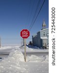 Small photo of Multilingual octagon red stop sign with in Inuktitut (Syllabic), English and French snow on the ground