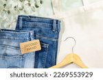 Small photo of Sustainable still life with djinns with label Second Hand, textile bag and hanger. Second hand clothing shop. Circular fashion, eco friendly sustainable shopping, thrifty shop concept. Flat lay