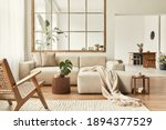 Small photo of Modern interior of open space with design modular sofa, furniture, wooden coffee tables, plaid, pillows, tropical plants and elegant personal accessories in stylish home decor. Neutral living room.