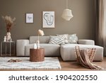 Small photo of Interior design of stylish living room with modern neutral sofa, mock up poster farmes, dried flowers in vase, coffee tables, decoration and elegant personal accessories in home decor. Template.
