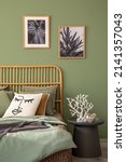 Small photo of Elegant bedroom interior design with mock up poster frames, bamboo bed, modern bedclothes, side table and stylish accessories. Eucalyptus wall. Template. Copy space.