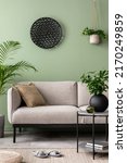 Small photo of The stylish composition at living room interior with green wall, design gray sofa, coffee table, dark ornament and elegant personal accessories. Beige pillow. Cozy apartment. Template.
