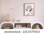 Small photo of Interior design of harmonized living room with mock up poster frame, white commode, vase with leafs, decoration and personal accessories. Cozy home decor. Template.