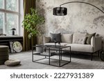 Industrial and loft living room interior with concrete wall, gray sofa, modern armchair, simple black coffee table, green pillows, curtain, books and personal accessories. Home decor. Template. 