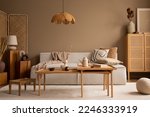Creative composition of living room interior with modular sofa, wooden coffee table, rattan sideboard, beige rug, pillows and personal accessories. Home decor. Template. 