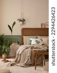 Small photo of Warm and cozy bedroom interior with mock up poster frame, boho bed, beige bedding, green wall with stucco, books, brown slippers, plants in pots and personal accessories. Home decor. Template.