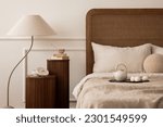Small photo of Warm living room interior with cozy bed, beige bedding, lamp, stylish wooden stand, slippers, bright pitcher, books, trace, wall with stucco and personal accessories. Home decor. Template.