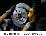 Small photo of Car mechanic installing two piston brake calipers and disc brake rotor.