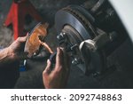 Small photo of Auto mechanic applying a high temp brake grease on the brake pads.