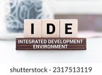 Small photo of IDE - Integrated Development Environment - software application that provides comprehensive facilities to computer programmers for software development, acronym concept on notepad