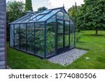 A Small Greenhouse Stands In A...