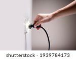 Small photo of Wet hand connecting electrical plug cause electric shock, Idea for causes of home fire, Electric short circuit, Electrical hazard can ignite household items, Residential building electrical fires.