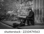 Small photo of Central District, Riga, LV-1050, Latvia October 2nd 2022 A male busker playing a keyboard on the doorstep of an old church in Riga Old Town. Black and white
