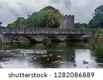 Old stone bridge over Glenarm River with ducks and castle tower, Glenarm, Northern Ireland