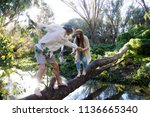 Young loving couple crossing a stream on a fallen log in Secret Garden, Gwelup, Careniup, Western Australia.