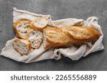 Rustic French sourdough baguette on a towel on a gray table, top view