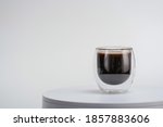 Transparent double wall glass, with black coffee, on white background. Cup with black liquid on white rotating table. Easy to use for advertising branding and marketing. 