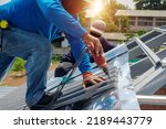 Small photo of Roof repair, worker replacing gray tiles or shingles on house with blue sky as background and copy space, Roofing - construction worker standing on a roof covering it with tiles.