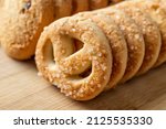 Small photo of Sugar pretzel macro. Crispy shortbread pretzels with sugar in a row on a wooden background. Tasty butter biscuits. Baked pastry for breakfast. Sweet food, dessert and snack concepts. Front view.
