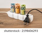 Small photo of Unplugged electric plug at power strip with rolled euro currency banknotes on a floor. Electric bill increases in Europe. Energy price spike. Soaring of electricity prices. Front view.