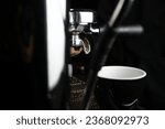 Small photo of Espresso drip shot with double spout portafilter from coffee machine. Coffee beans roasting process espresso machine. Coffee drip coming out of the spout.