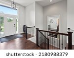Entry way and staircase with large mirror on wall, hardwood floors and sky lights looking to greenspace