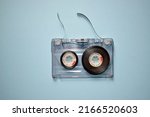 Audio cassette with torn tape on a blue background, top view.