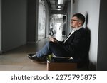 Small photo of Portrait of sad dismissed senior old business man worker taking his office supplies in the box. Pensioner mature retire from work carry staff back home. Lifestyle business retirement, quit job concept