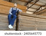 Small photo of Industrial warehouse of a sawmill, an employee puts his hands on the finished products at the sawmill in the open air
