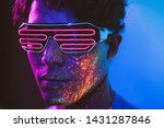 Small photo of Handsome boy dancing at the rave party with fluorescent paintings on his face