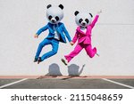 Small photo of Storytelling image of a couple wearing giant panda head and colored suits. Man and woman making party in a parking lot.