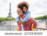 Small photo of Black cheerful happy couple in love visiting Paris city centre and Eiffel Tower - African american tourists travelling in Europe and dating outdoors