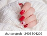 Beautiful female hand with red manicure nails, heart and Valentine's day design