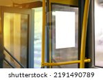 Open bus door entrance with yellow handrail and copy space empty poster on a window. Infrastructure. Door. No People. Waiting. Inside. Mock. Ride. System. Seat. Frame. Copy space