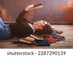 Small photo of A relaxed woman underlie and reads in a room full of books.