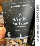 Small photo of Chicago, IL, USA - July 8 2023: A copy of the graphic novel version of Madeleine L'Engle's A Wrinkle in Time being pulled off a bookshelf