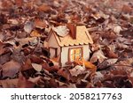 Eco-friendly home. Wooden house with fallen autumn leaves. model of a wooden house in the forest, cozy light from the window, a dream for a happy family life