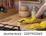 cleaning the kitchen with a sponge, hands in yellow protective rubber gloves wash the kitchen