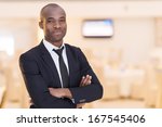 Confidence and charisma. Cheerful young African man in full suit keeping arms crossed and looking at camera