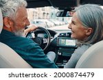 Rear view of active senior couple enjoying car ride while sitting on front seats of the car