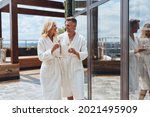 Beautiful mature couple in bathrobes enjoying champagne while relaxing in luxury hotel outdoors