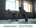 Young fit couple looking concentrated while exercising in gym together