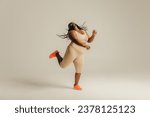 Full length of happy curvy African woman in sportswear dancing on studio background