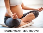 Meditating on maternity. Close-up of pregnant woman meditating while sitting in lotus position